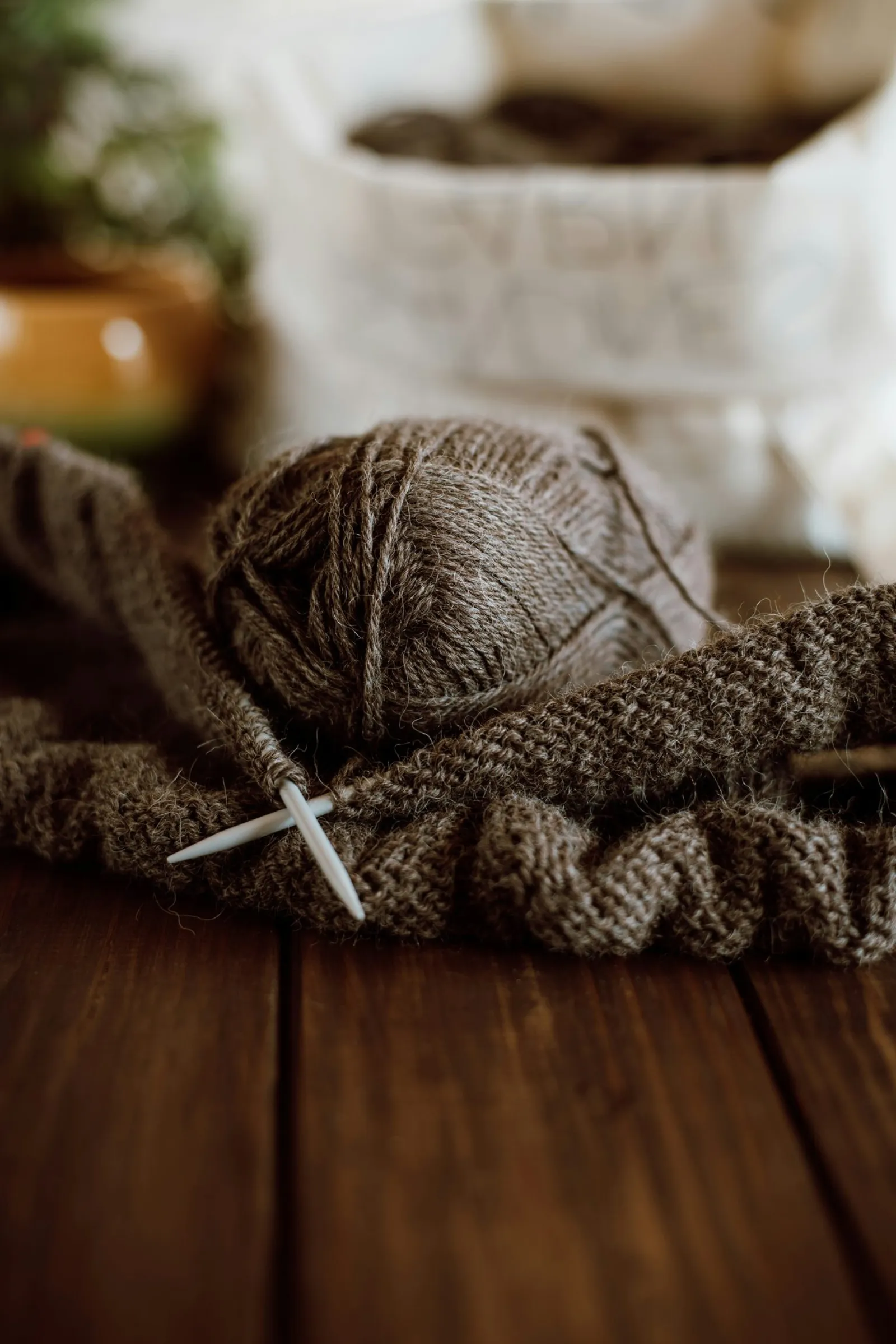 Brown knitting on needles next to a ball of yarn
