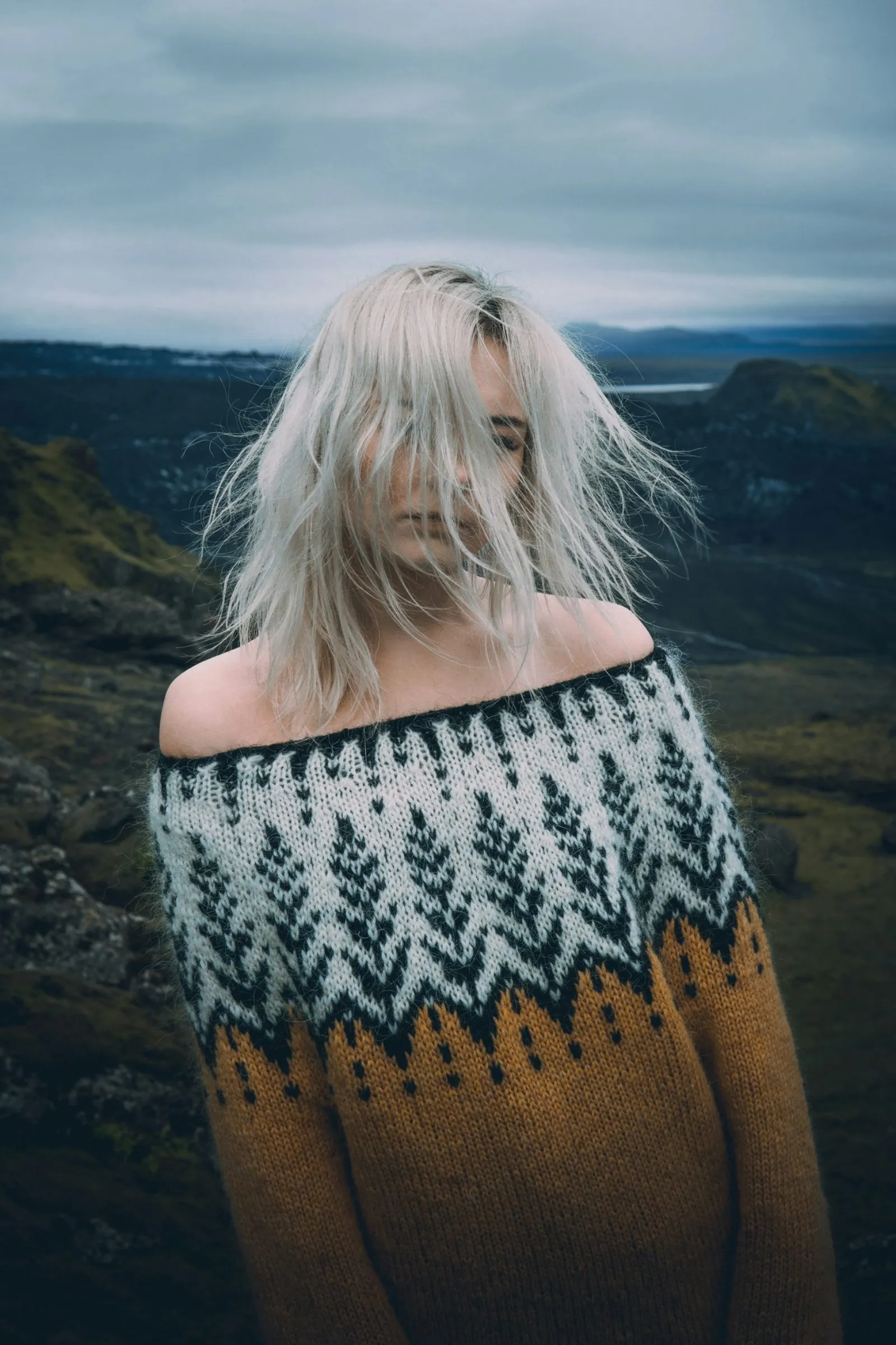 An Icelandic-style yoke sweater in a moorland landscape, worn by a person whose face is hidden by their hair